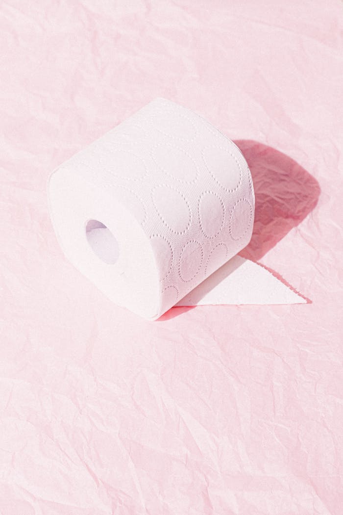 A toilet paper roll on crinkled pink paper with bright lighting.